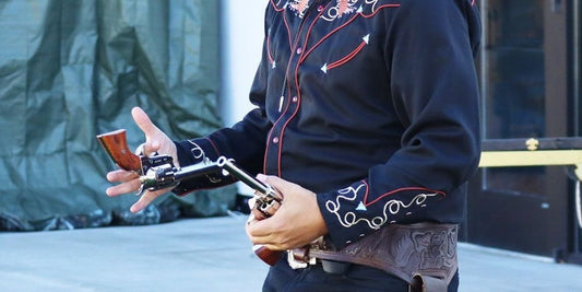 man in cowboy costume juggles in front of audience