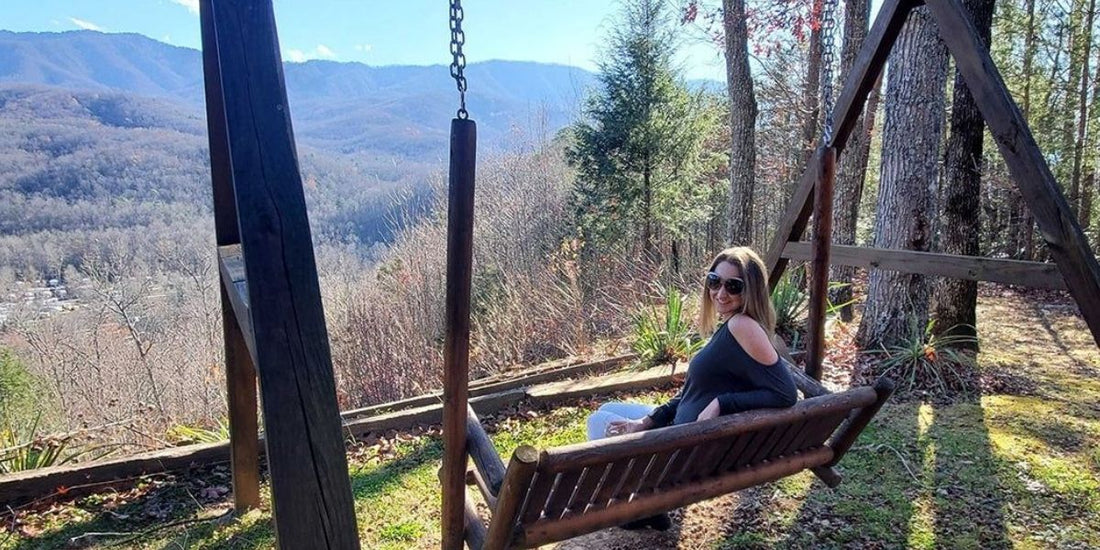 woman sits on swing overlooking great smoky mountains on a warm winter day