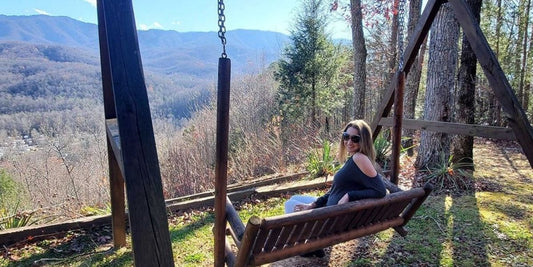 woman sits on swing overlooking great smoky mountains on a warm winter day
