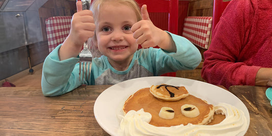 a child gives a thumbs up over her bear shaped pancakes at frizzle chicken farmhouse in pigeon forge